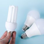Close-up of energy-saving CFL and LED light bulbs on a blue background, showcasing eco-friendly lighting solutions.