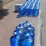 a row of blue water bottles sitting on the side of a road